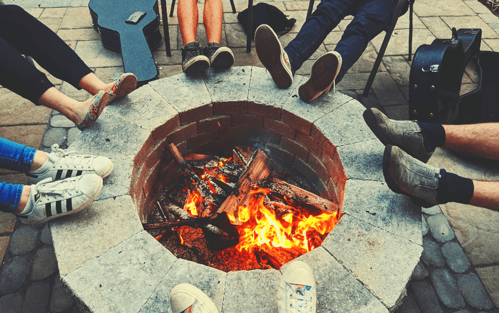 fire burning in a stone fire pit with several people sitting around it