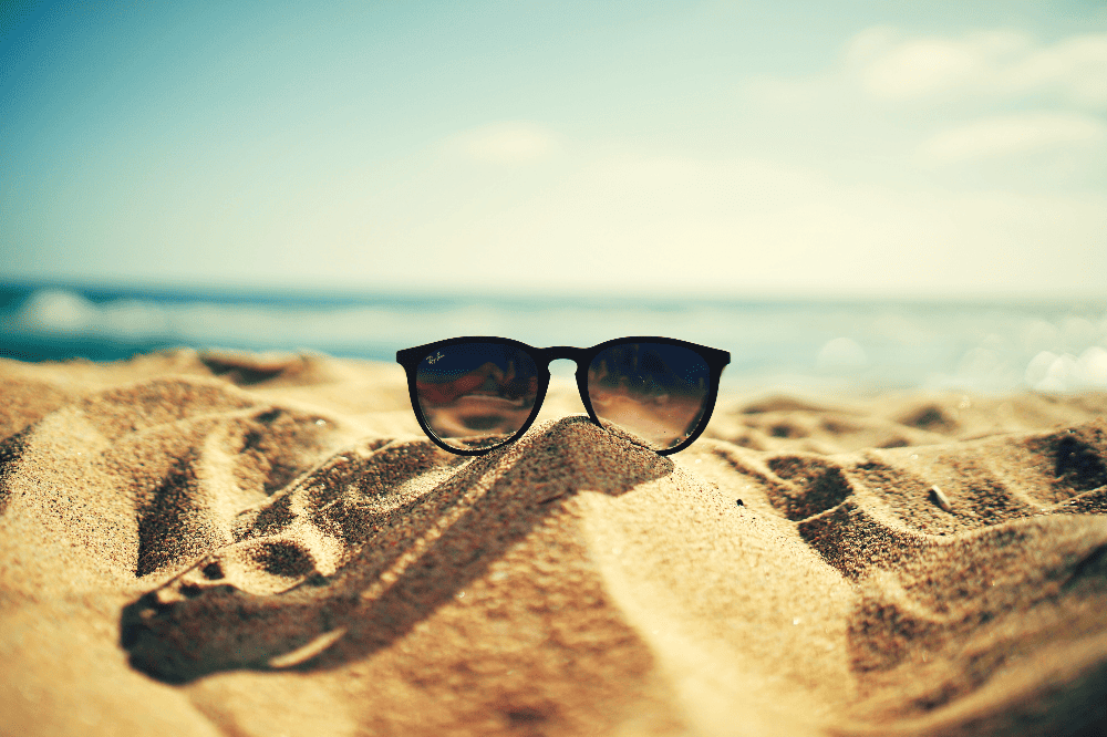 a pair of sunglasses resting on a pile of sand on the beach