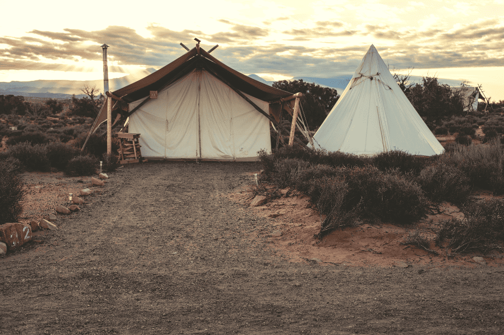 canvas tent next to a teepee in the desert