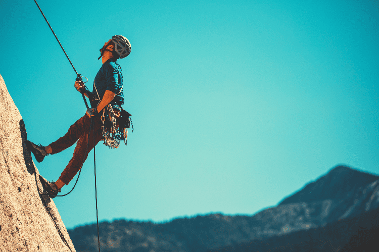 man rappelling down a rock face
