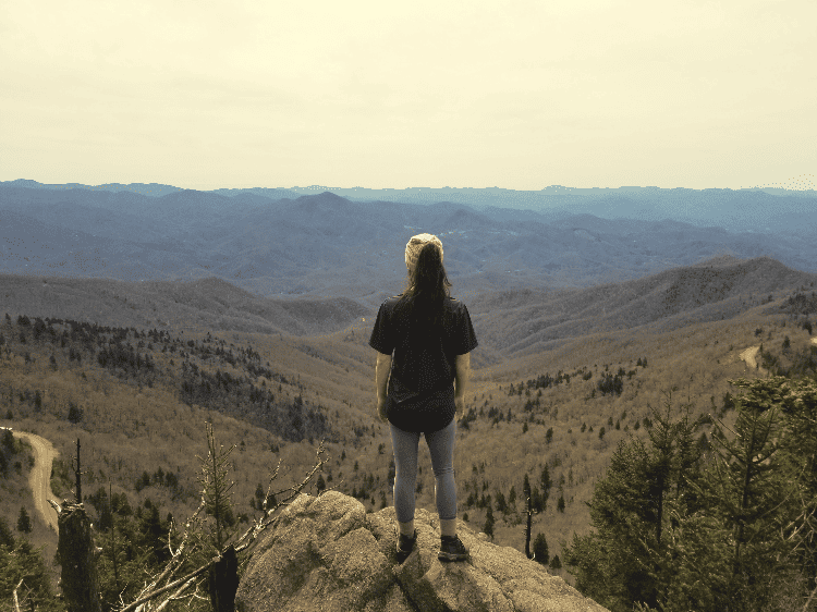 woman standing on top of a cliff