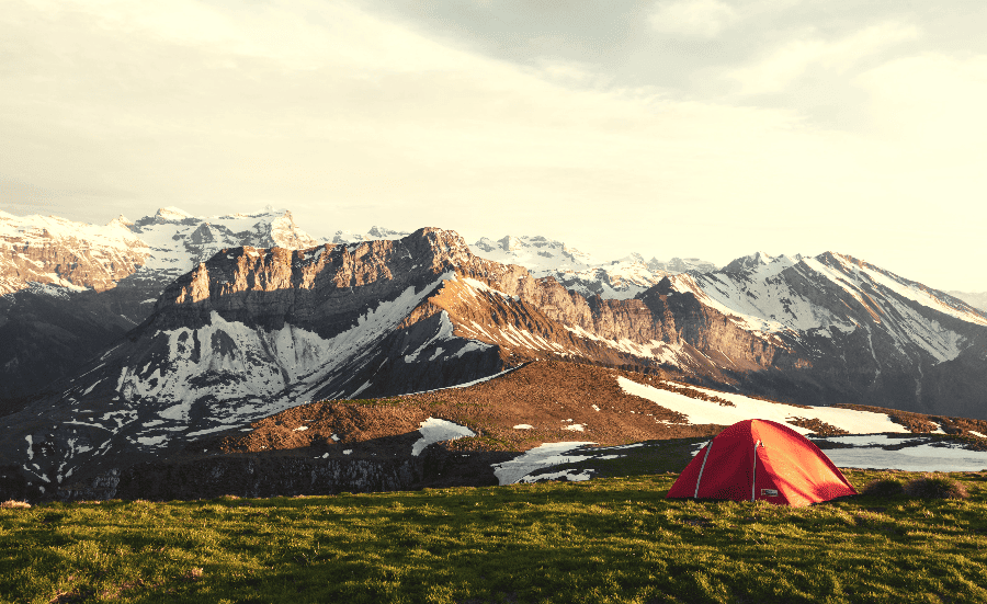 tent on a grassy plain next to mountains