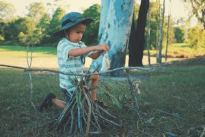 young boy putting sticks together to build a campfire