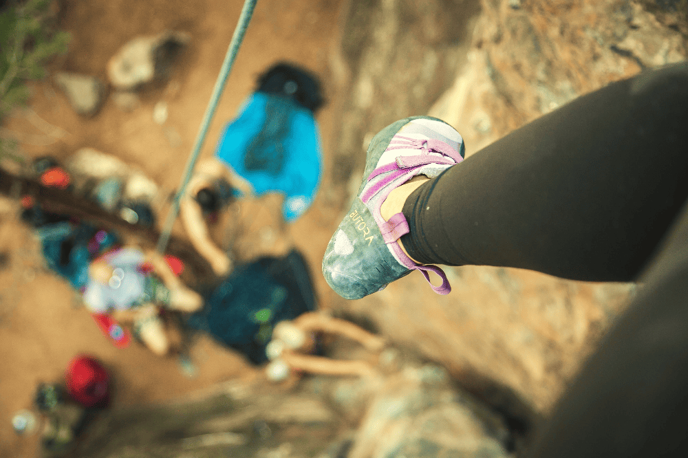 woman rock climbing with her shoes