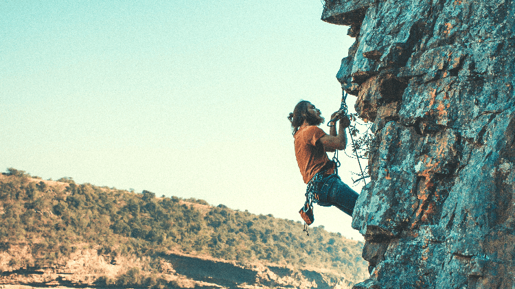 man doing anchor work while rock climbing