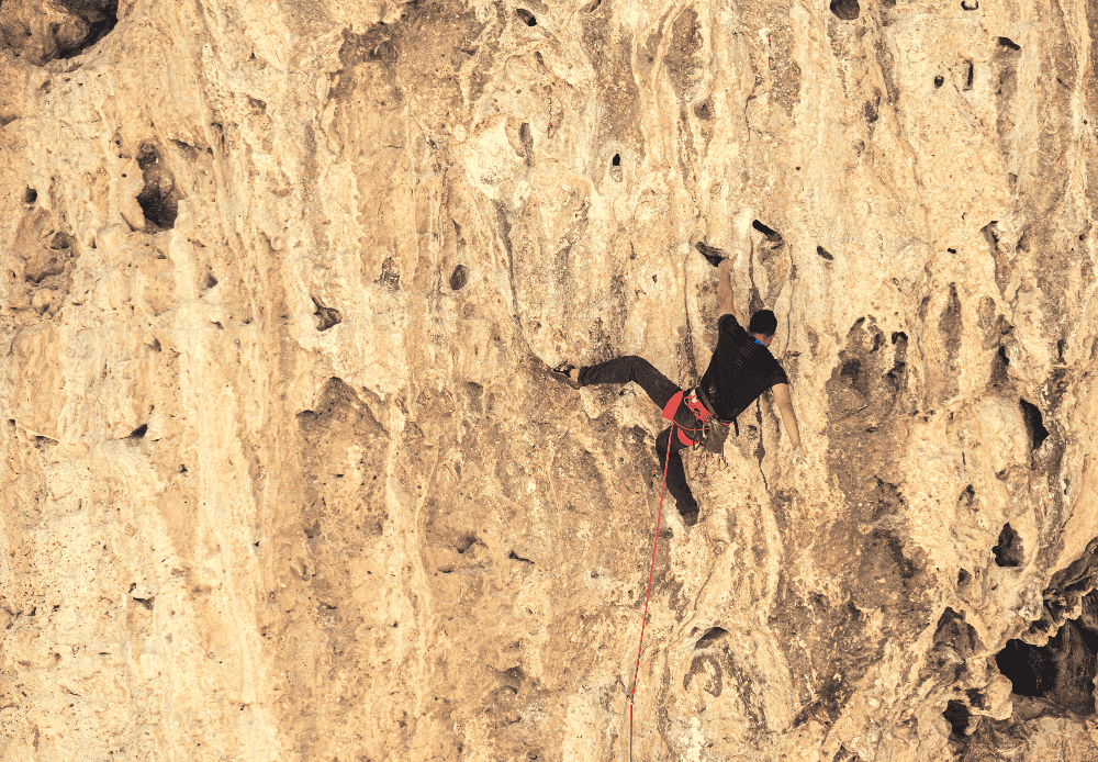 man sport climbing on a rock wall