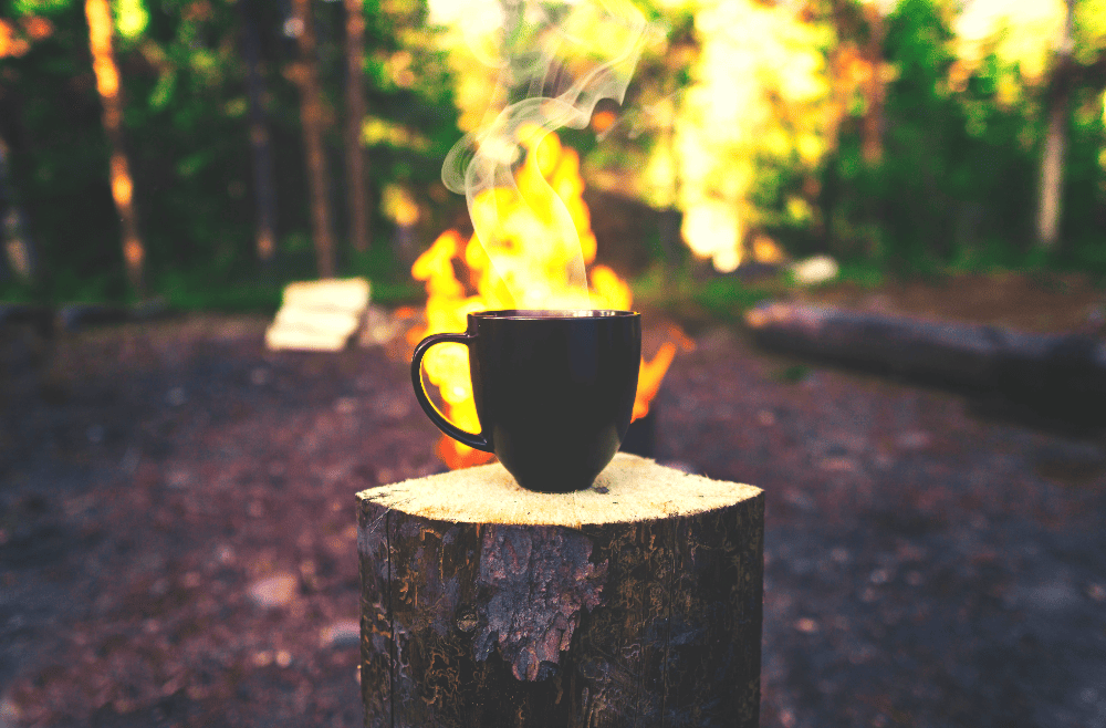 coffee mug on a stump in front of fire