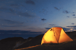 glowing tent on a ridge at dusk