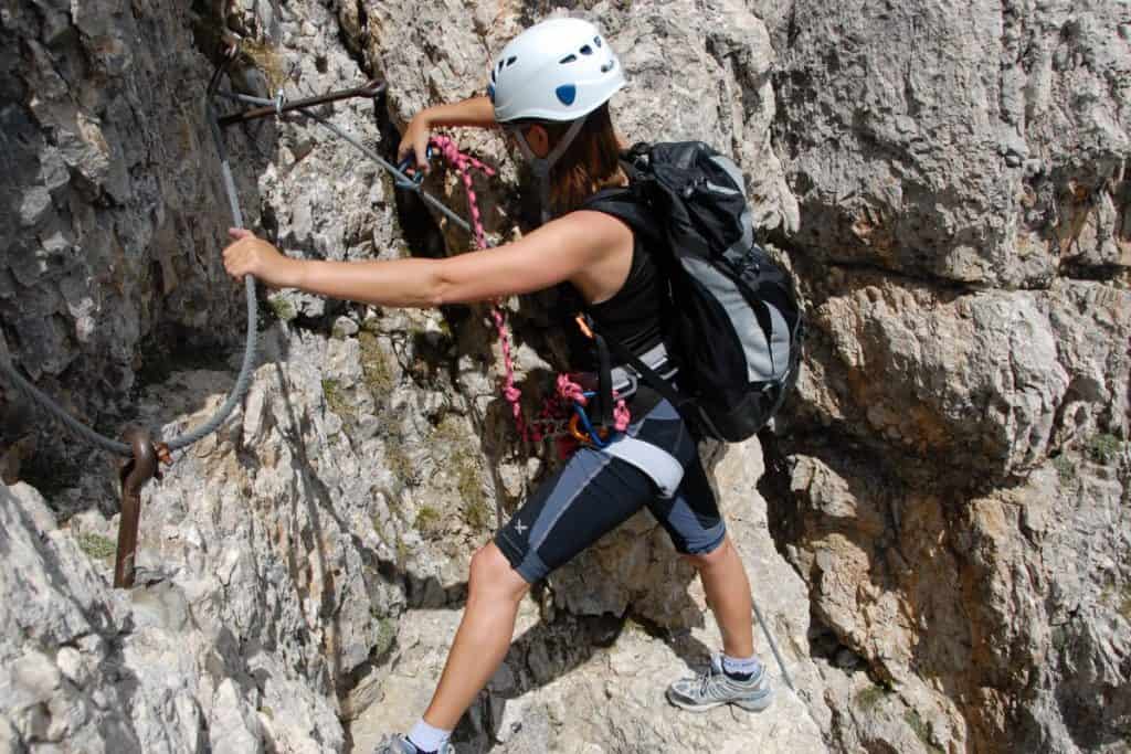 woman doing a via ferrata with a white helmet and backpack