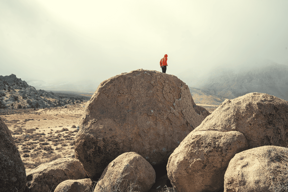 man standing on top of a boulder