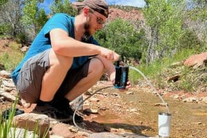 man in blue shirt purifying water from a creek in zion national park