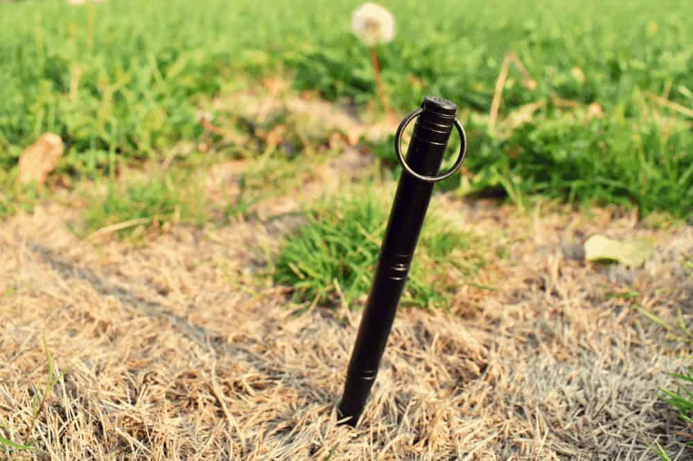 a pen driven into the ground surrounded by yellow and green grass