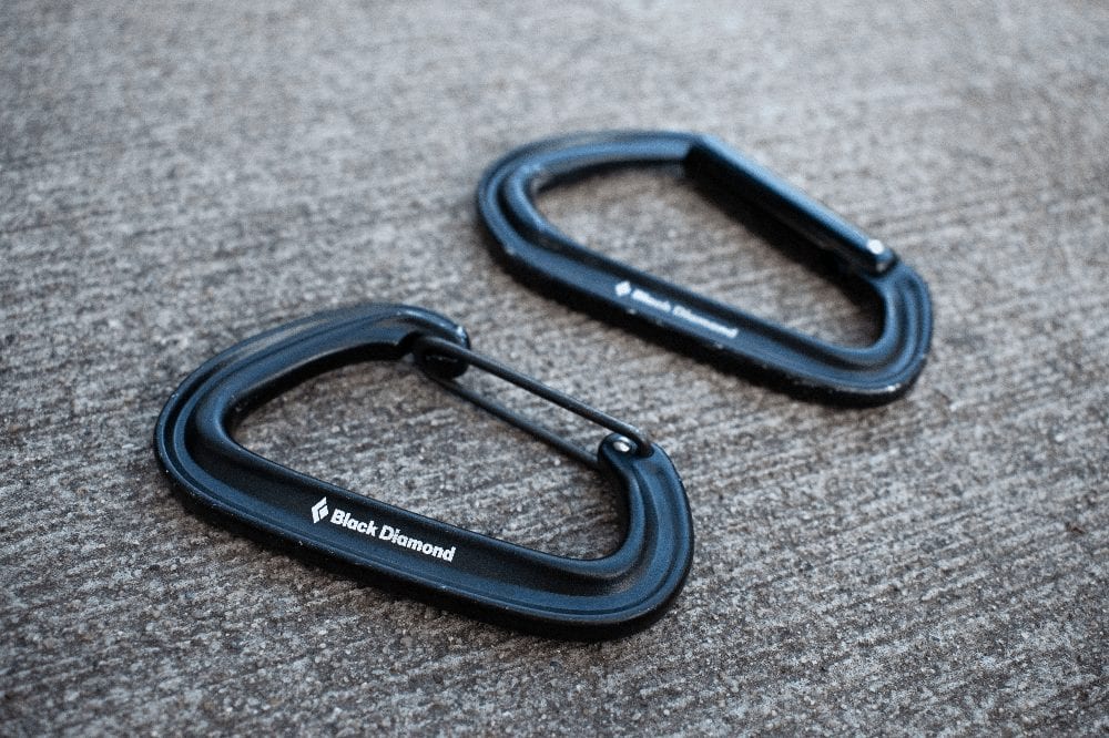 two black diamond carabiners laying next to each other on a sidewalk