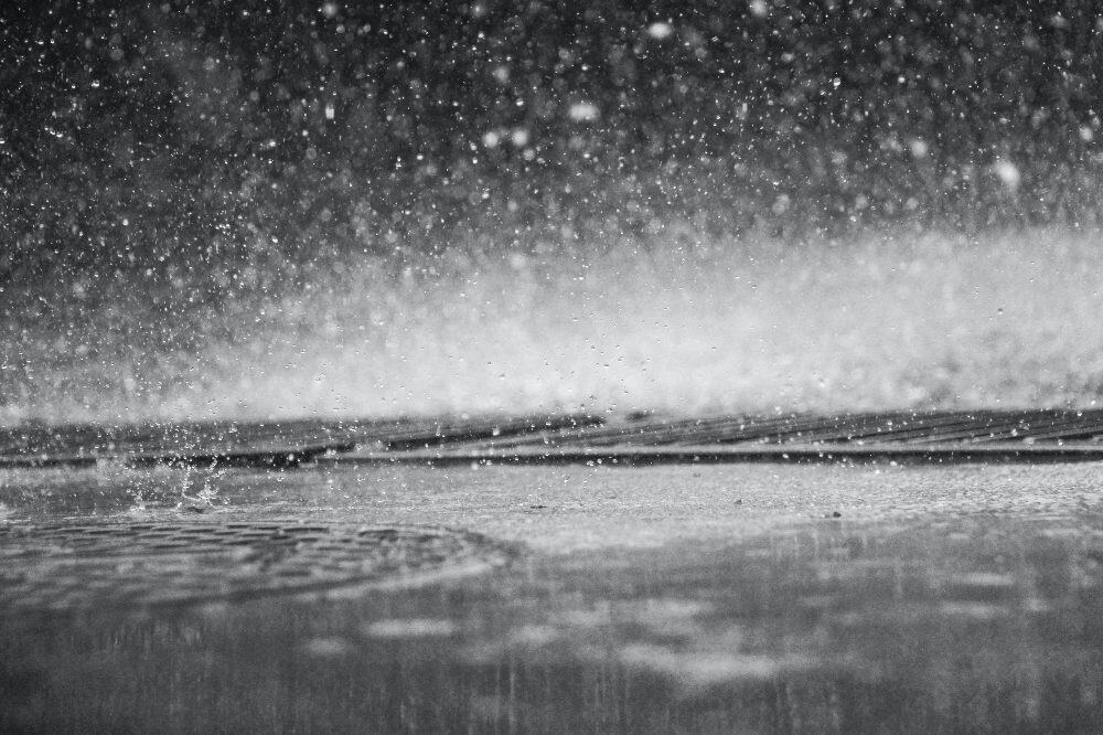 black and white photo of rain falling into a puddle