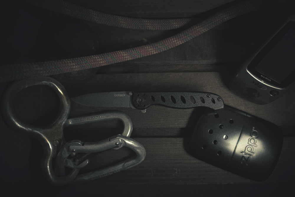 carabiners with a belay device rope and zippo lighter and knife