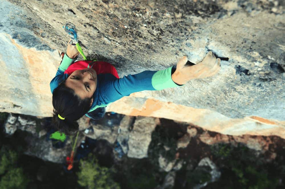 woman rock climbing big wall crimp carabiner
