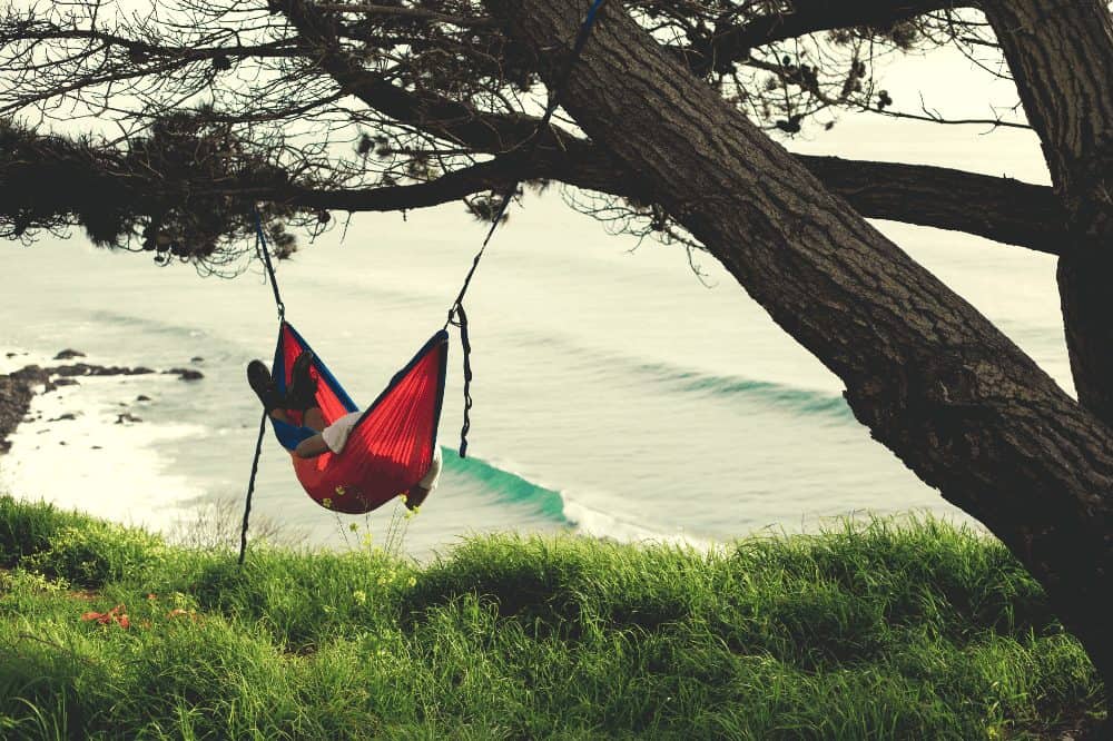 man in a hammock next to the ocean