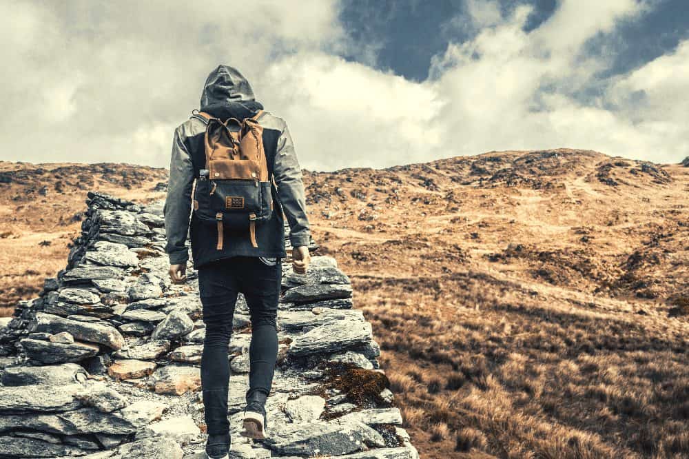 person hiking with a backpack and jacket on with the hood up