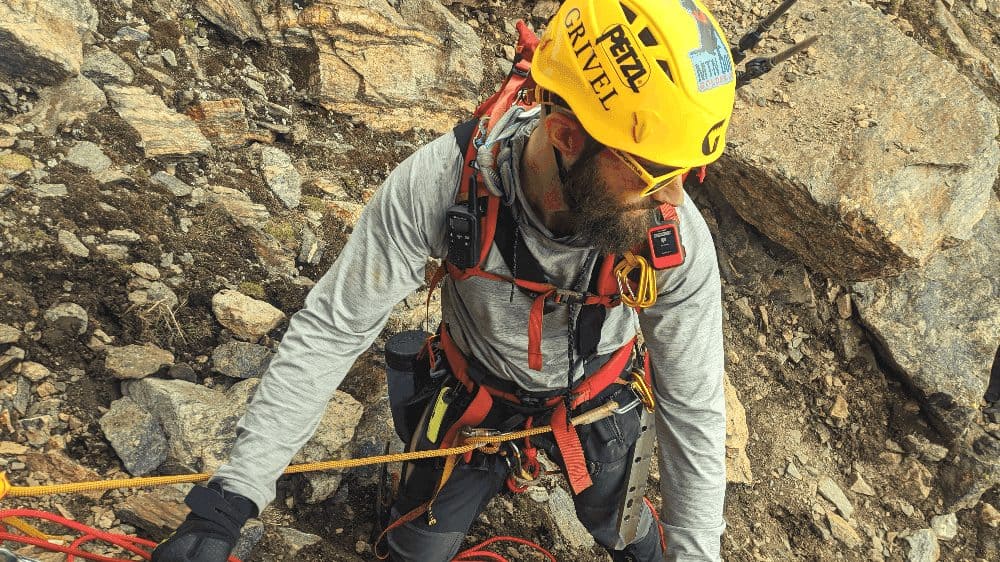 man in a yellow helmet tied into a rope while rock climbing