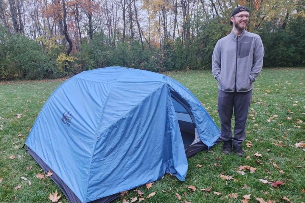 man standing by a blue tent outside