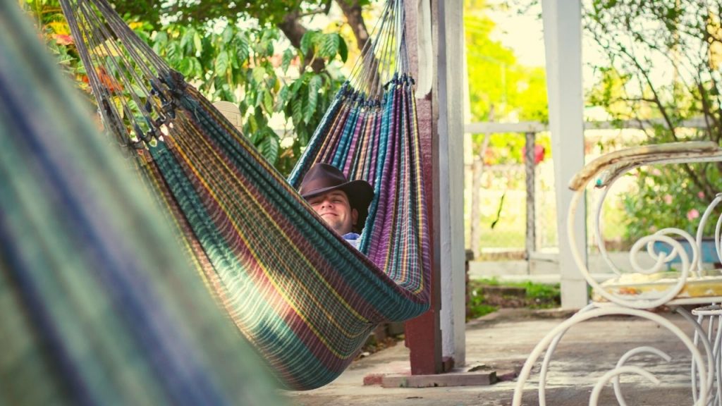 man in a cowboy hat laying in a hammock outside