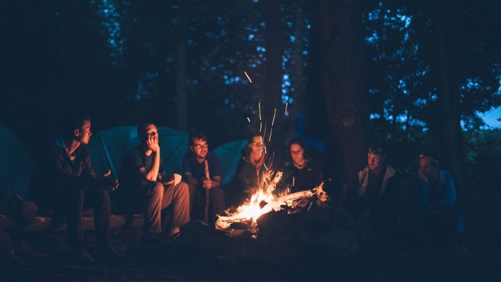group of people sitting around a campfire at night