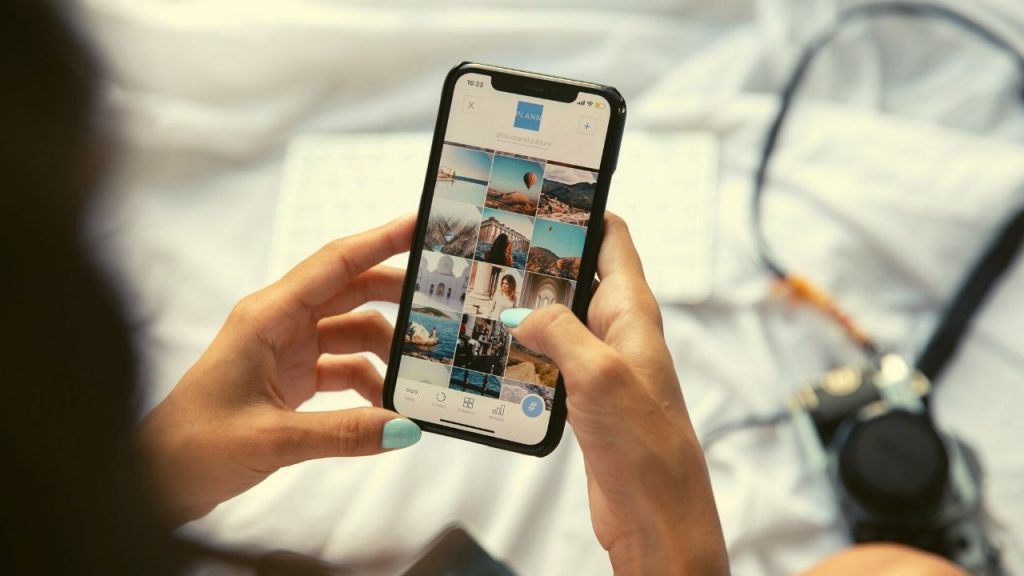 young girl with blue painted fingernails holding a smartphone while looking at instagram
