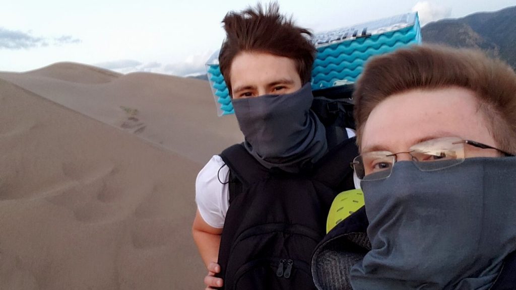 two men with face covering backpacking through a desert