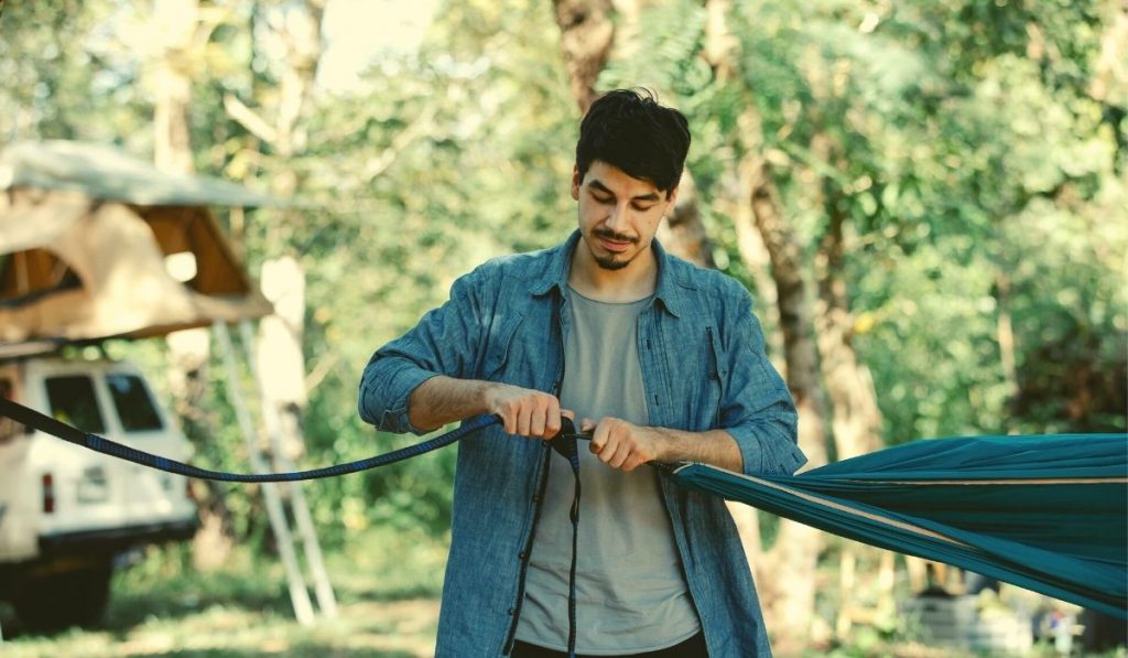 man attaching the suspension system to his hammock