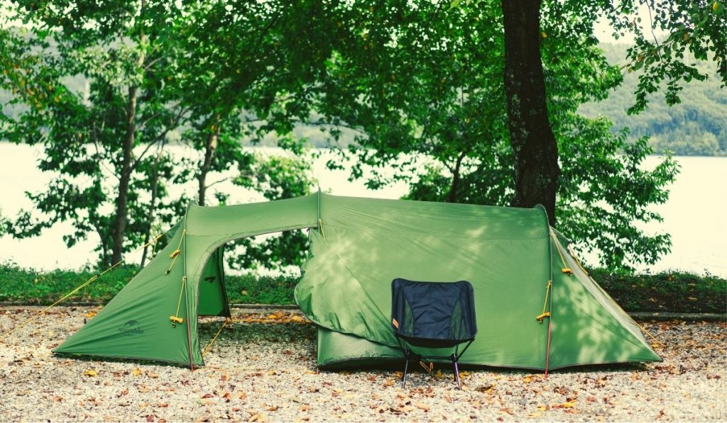 large green tent next to water and trees