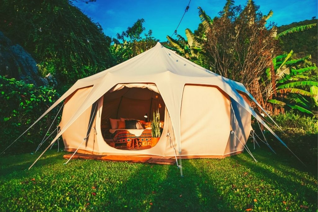 canvas yurt tent with an open door on green grass