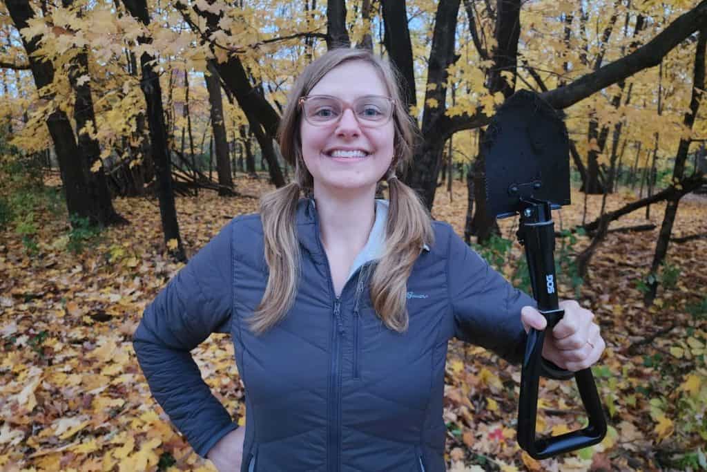 woman holding a black shovel in the forest