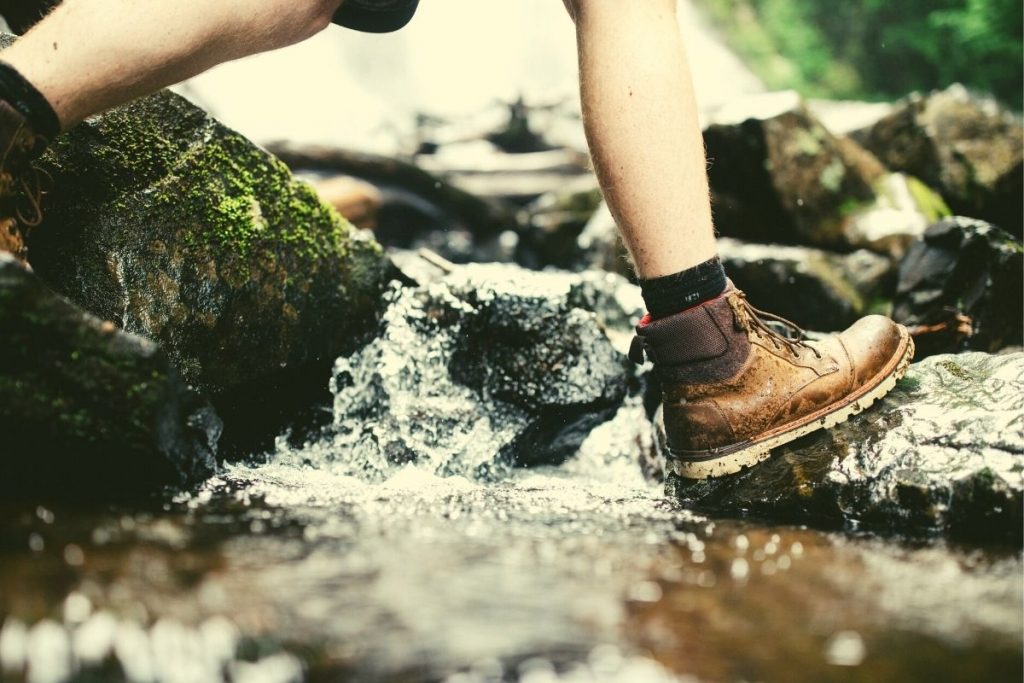 person walking with brown boots over a stream