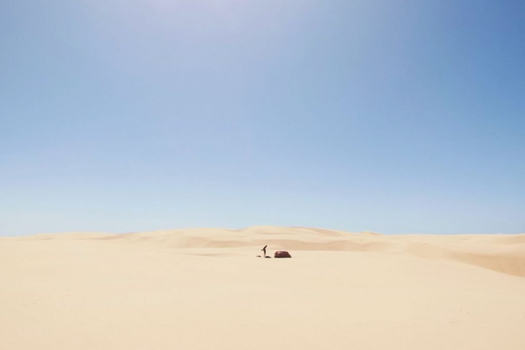 man with a tent in the desert under the sun