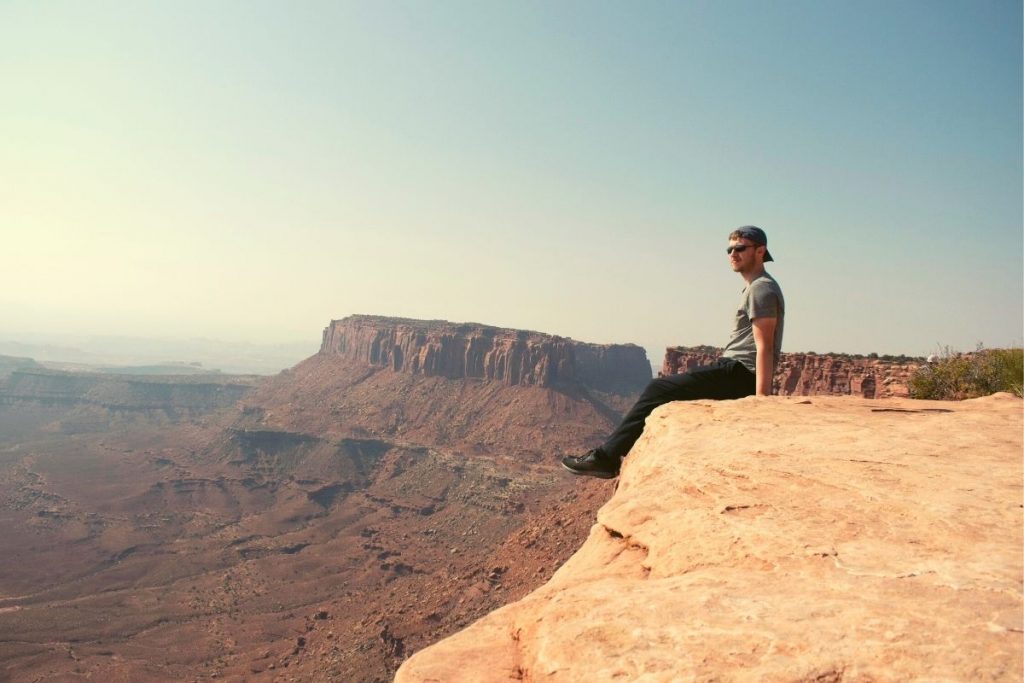 man sitting on the edge of a cliff in the canyonlands of Utah