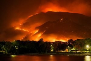 wildfire burning the side of a mountain next to a city at night