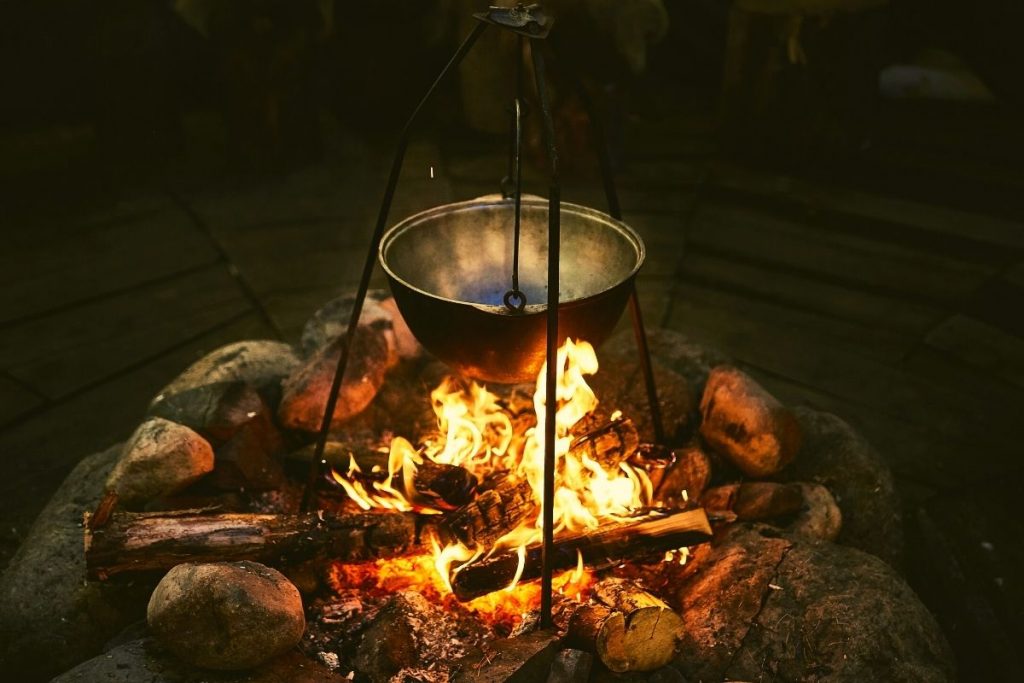 metal pot hanging over an open campfire