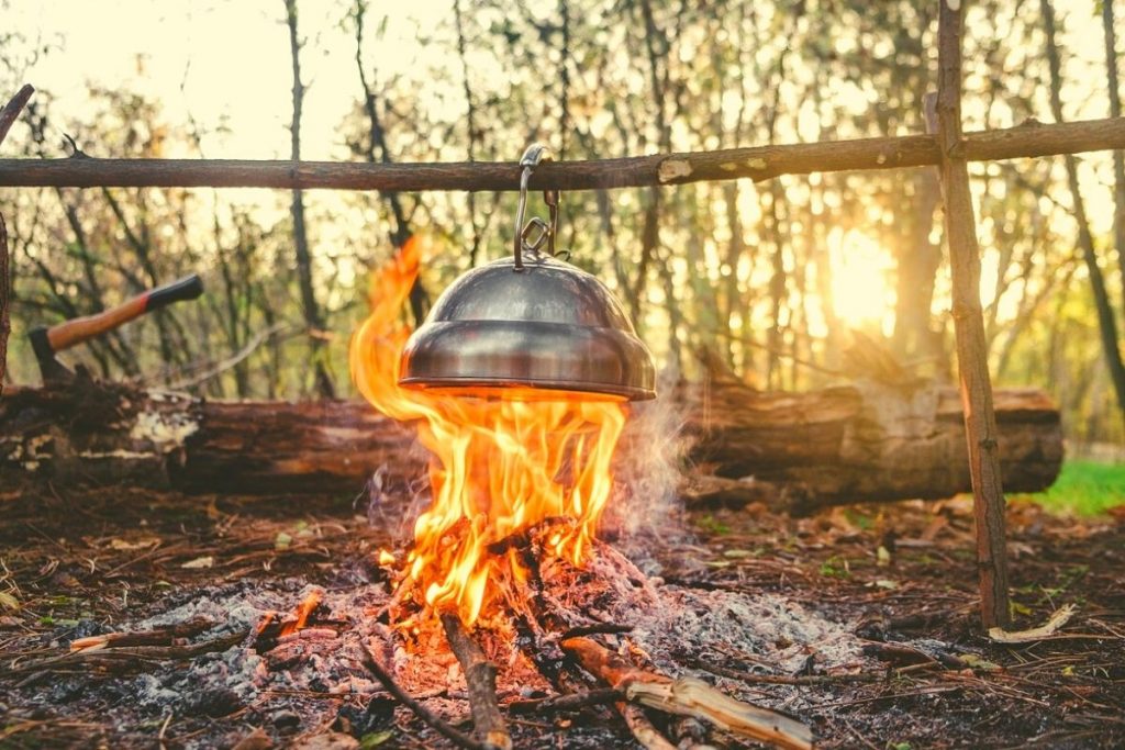 metal pot hanging over an open campfire