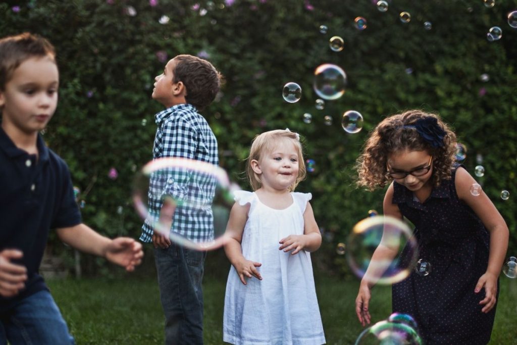 a group of kids playing with bubbles in the yard