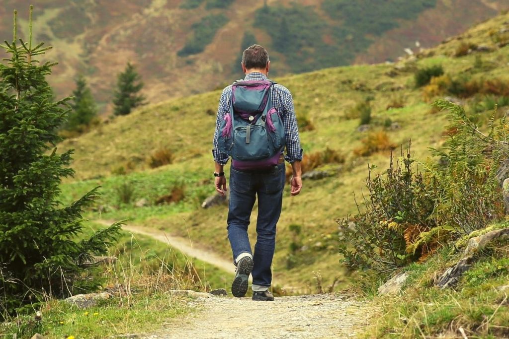 man with a blue backpack walking down a trail