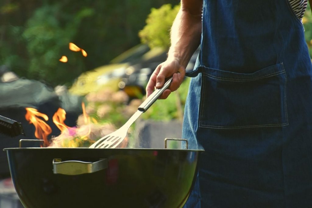 man cooking outside on a grill