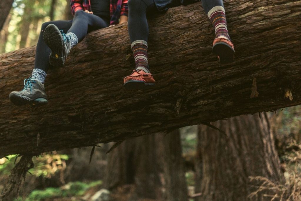 people sitting off a log with their shoes hanging over the edge
