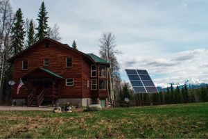 log house with solar panels green grass and dog with mountains