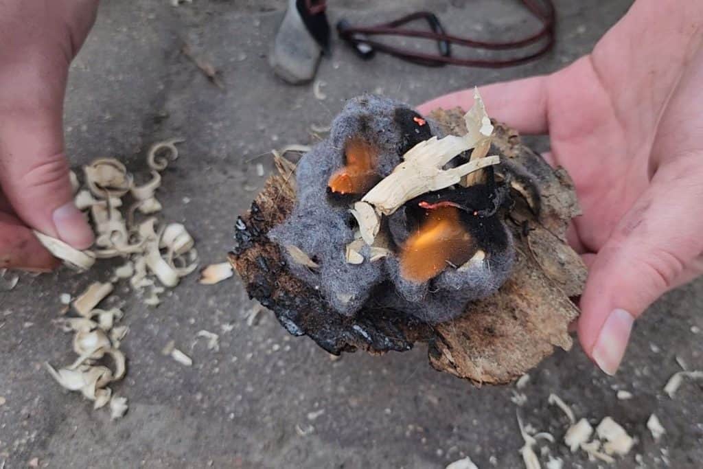 lit lint and wood on a piece of bark