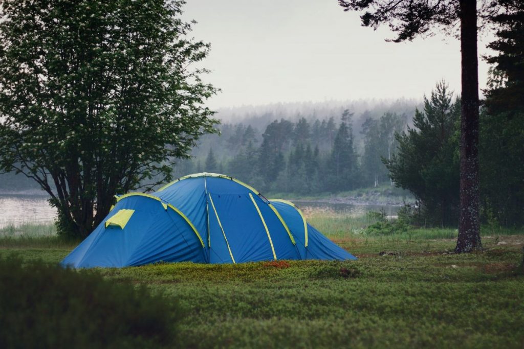 blue tent green grass trees cloudy sky