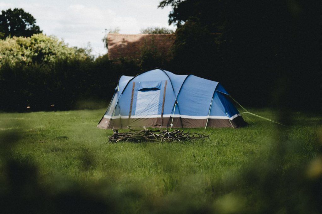 blue tent bushes green grass