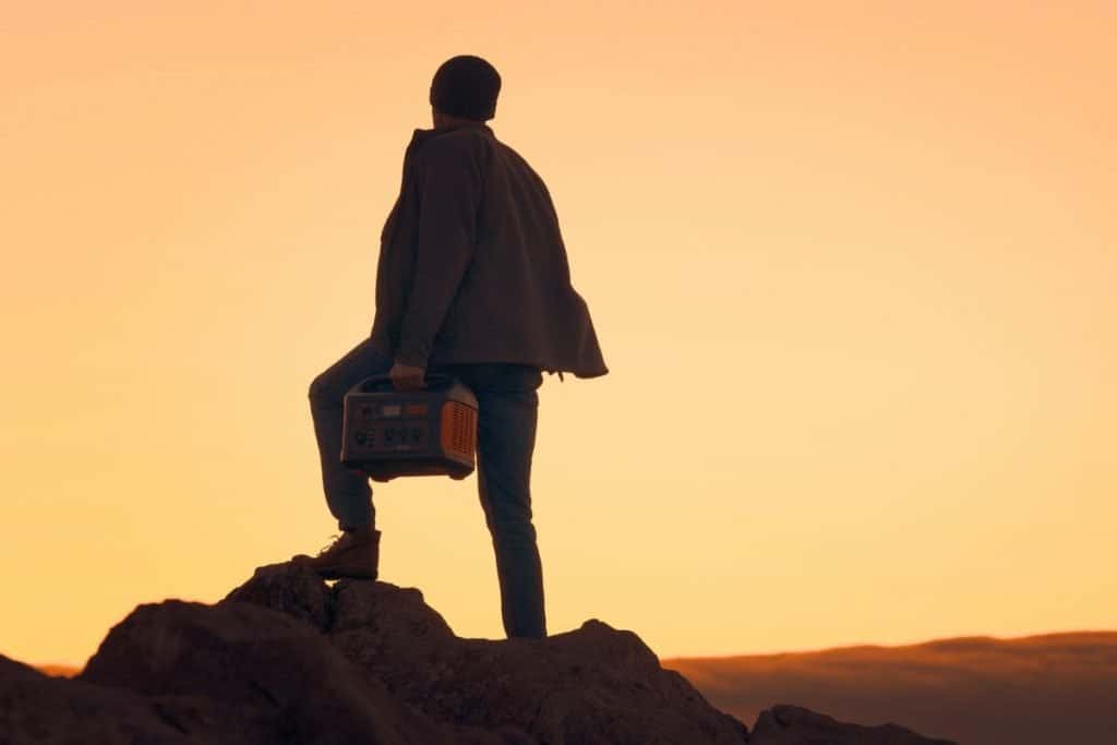 man holding generator mountain at sunset