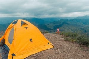 yellow tent in mountains stormy sky