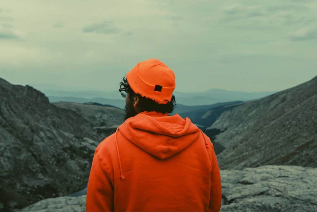 man with orange hat and sweater in mountains