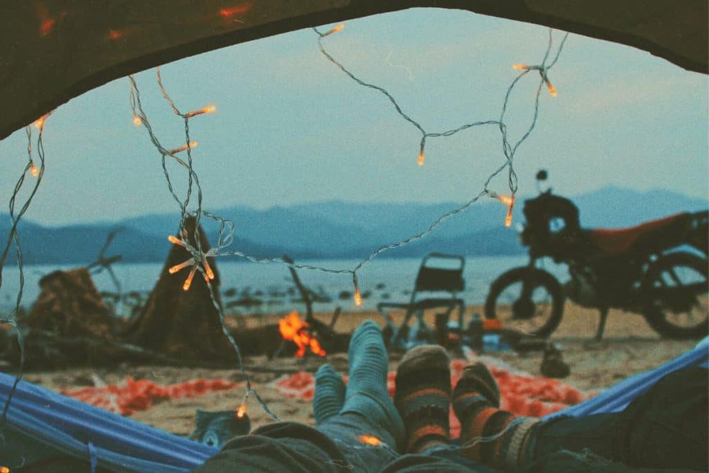 string lights on a tent with fire pit and motorcycle